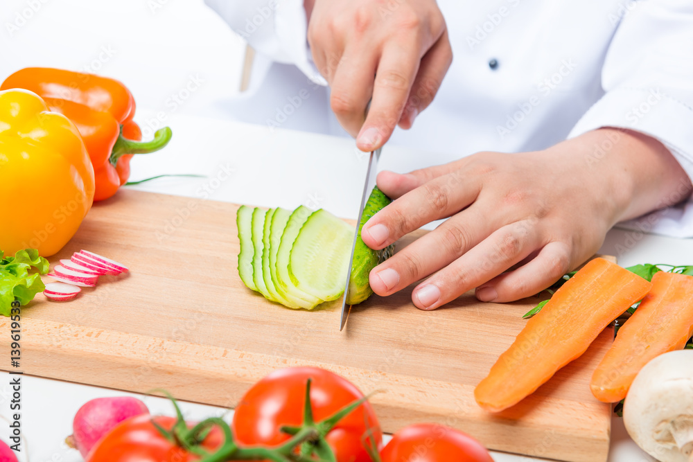 Chef cuts the cucumber salad carefully on a wooden cutting board Chef cuts the cucumber salad carefully on a wooden cutting board