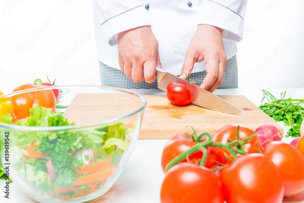 Chef in uniform cuts the organic vegetables in a glass bowl Chef in uniform cuts the organic vegetables in a glass bowl