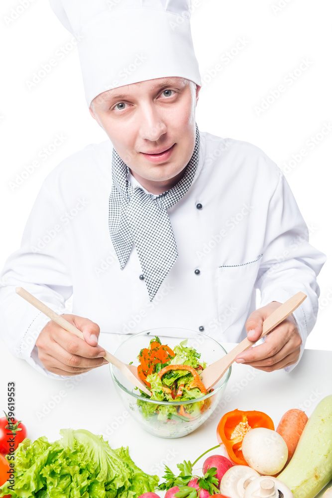 30-year-old chef is mixing a salad in a bowl with spoons