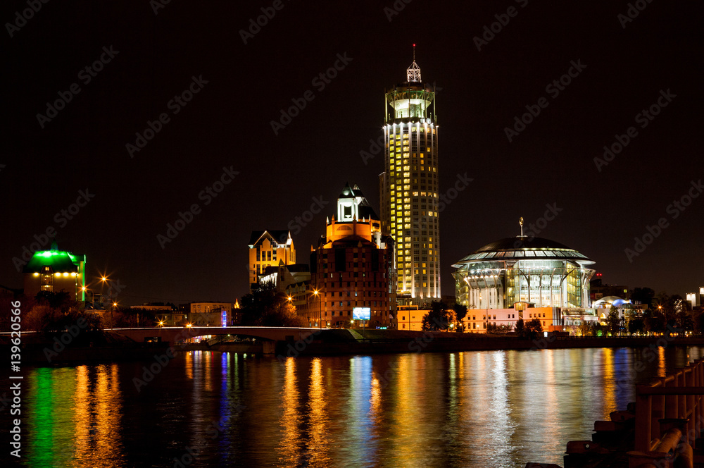 Night panorama of the Moscow House of Music is reflected in the Moscow river, Russia.