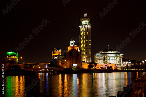 Night panorama of the Moscow House of Music is reflected in the Moscow river, Russia.