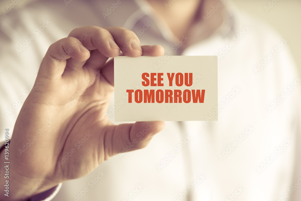 Businessman holding SEE YOU TOMORROW message card