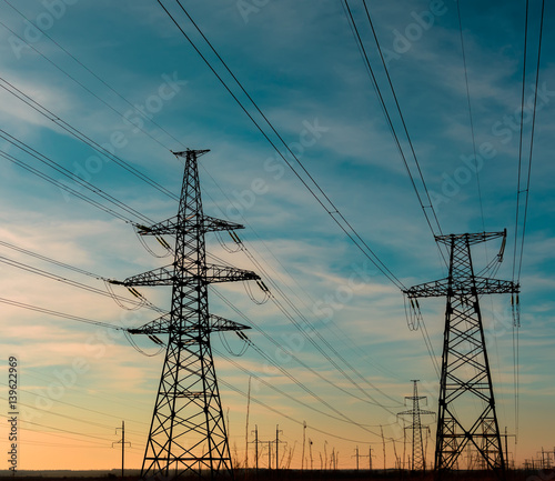 Electricity pylon silhouetted against blue sky background. High voltage tower.