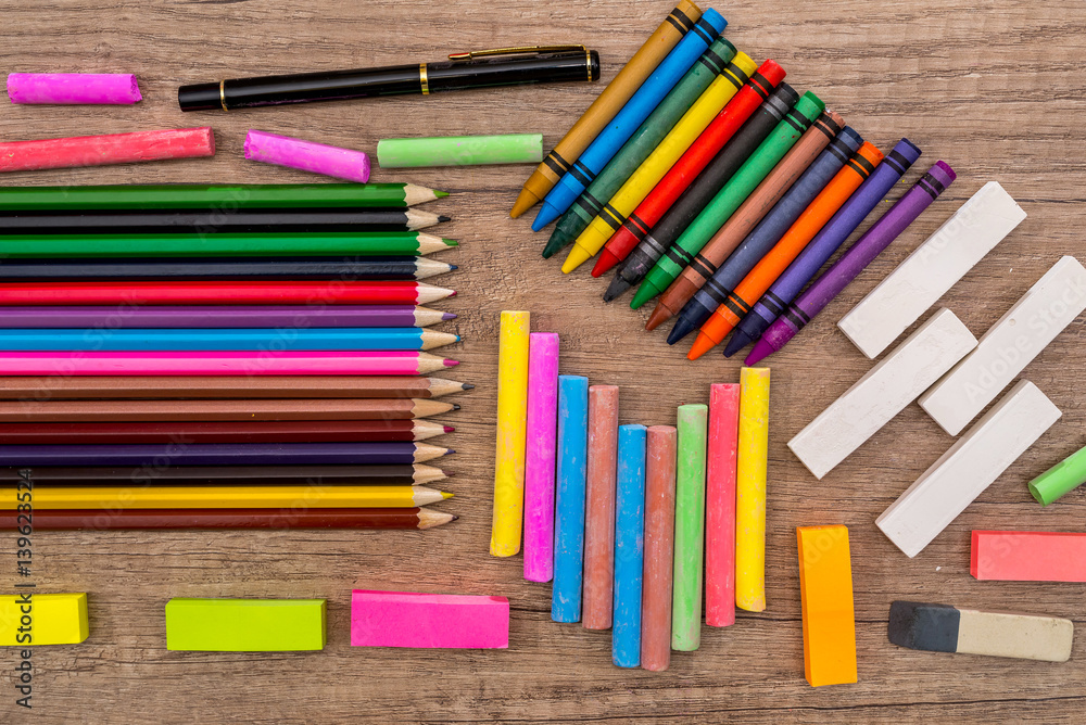 Fototapeta premium School Supplies - colored chalks and pencils on a wooden background.