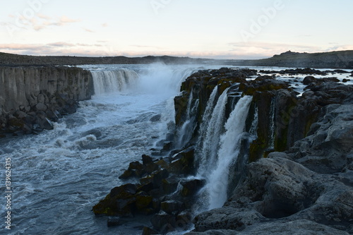Waterfall between cliffs Iceland sunset summer time