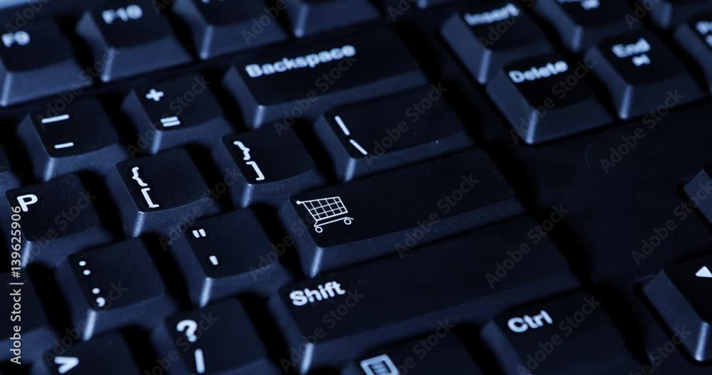 Close up of male hand pressing a shopping cart button on the computer keyboard Close up of male hand pressing a shopping cart button on the computer keyboard