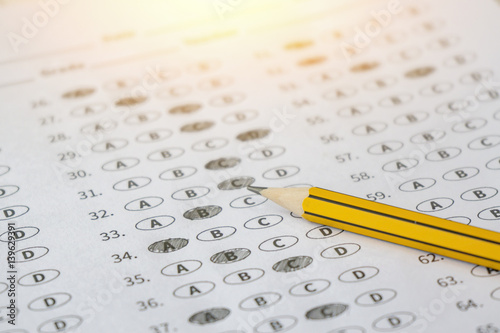 A pencil sitting on a test bubble sheet, optical form of an examination,Answer sheet with pencil,Standardized test form with answers bubbled and a black pencil,selective focus,vintage color