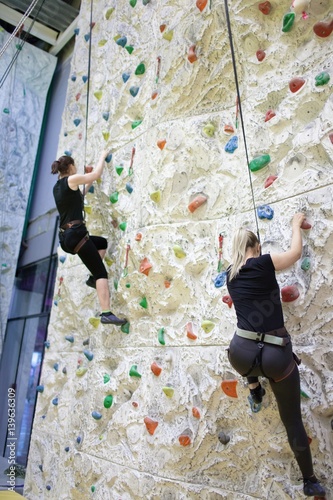 young sporty girls practicing rock-climbing on a rock wall indoors