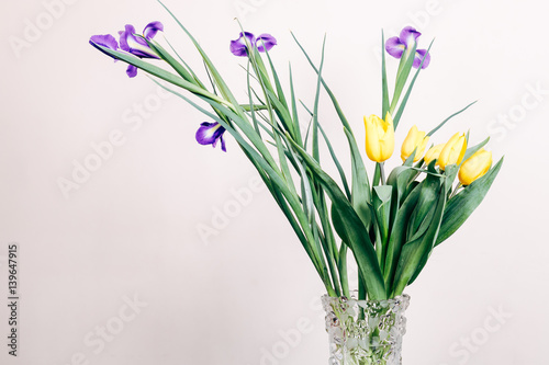 Yellow and purple flowers in a vase on a beige background