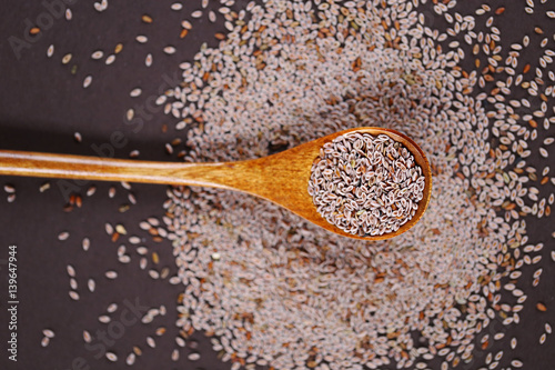 One small wooden spoon full of seeds of Indian plantain on a  brown background photo