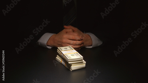 BRIBE: Businessman sits near a heap money on a table