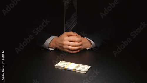 BRIBE: Businessman waits and puts a money on a table (US dollar)
