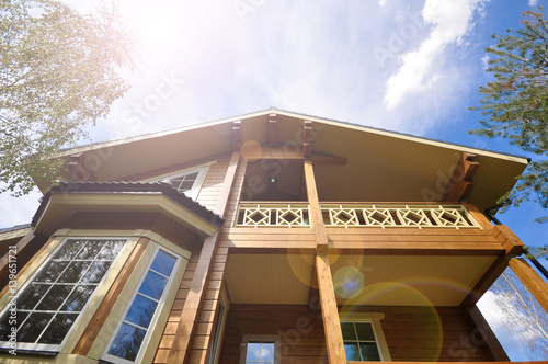 Modern facade of a wooden house on sky background and sunbeam