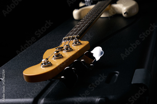 Tableau sur toile Electric Bass guitar headstock on black leather hard case isolated on black back