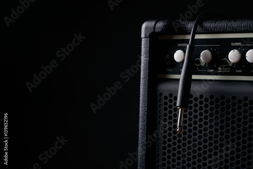 Close up of Black guitar amplifier with jack cable on black background.