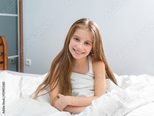 kid with long hair sitting in pajamas