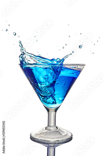 Splash in glass of a blue alcoholic cocktail drink with ice