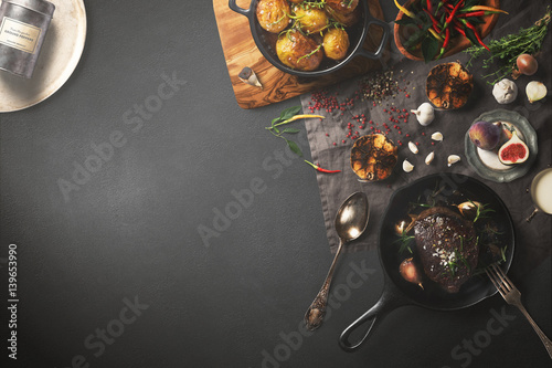 Overhead view of colorful roast vegetables, savory sauces and salt served with grilled t-bone steak on a rustic wooden counter in a country steakhouse created digital illustration photo