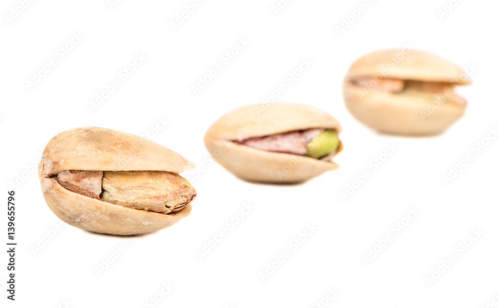 Fototapeta premium Three salted pistachio nuts on white background