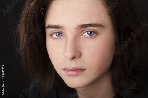 A portrait of a handsome blue eyes teenager on dark background