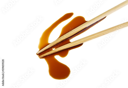 Splashes of soy sauce and chopsticks isolated on white background