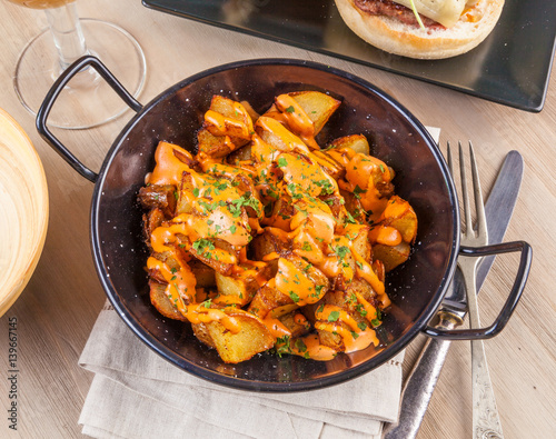 Patatas bravas, spicy potatoes, a typical Spanish dish with fried potato cubes and a spicy garlic sauce. photo