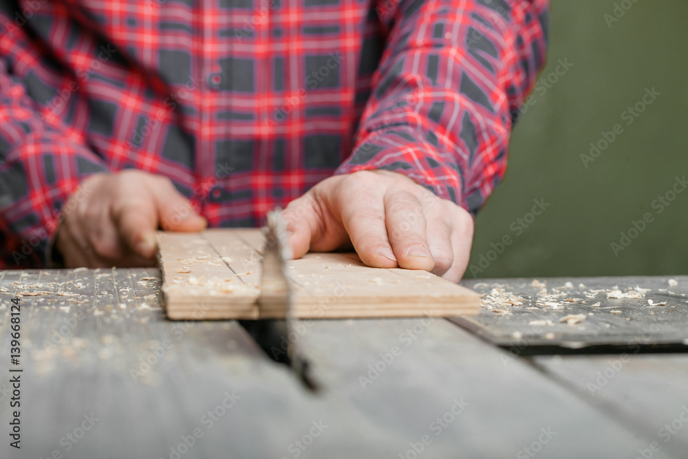 Carpenter working with table saw in workshop. Close-up.