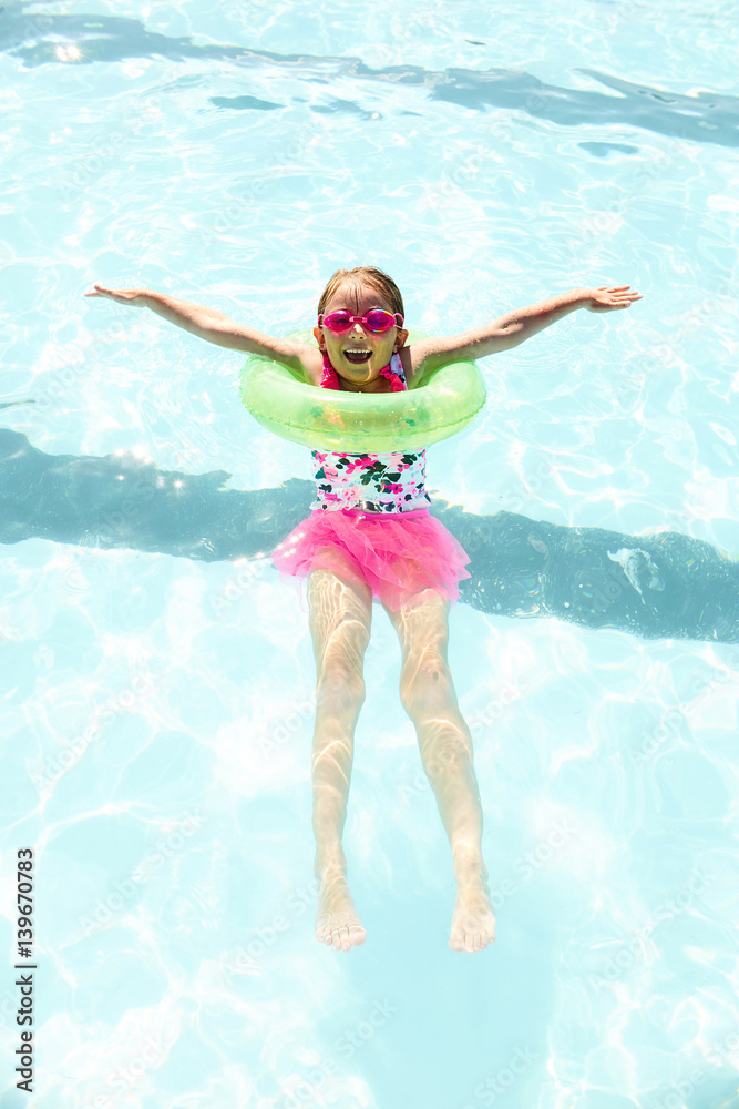 Cheerful little girl swimming with floating ring