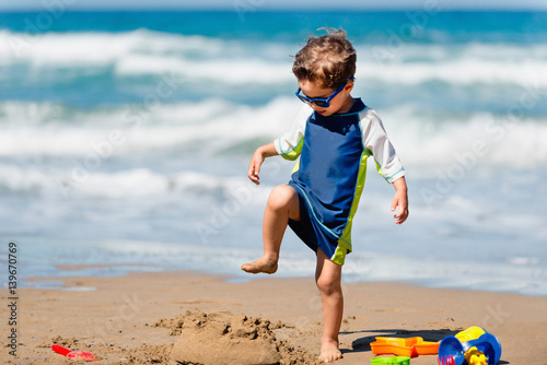 Canvas Print Cute boy demolishing sand castle