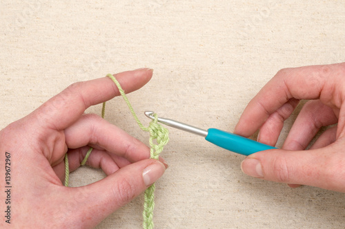 Hands Stitching a Chain of Green Yarn Using Knitting Hook