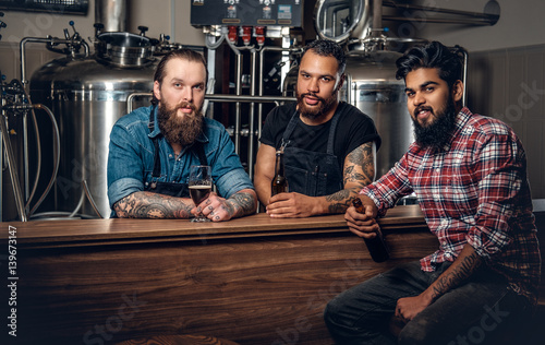 Stylishthree men men drinking craft beer in the microbrewery.