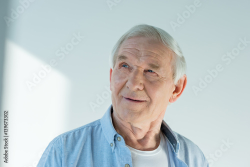portrait of pensive senior man in stylish shirt on white