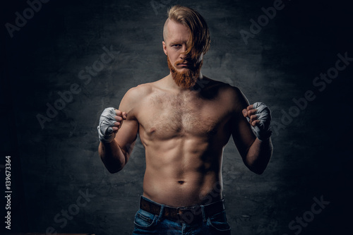 Brutal fighter with long hair over dark grey background. © Fxquadro