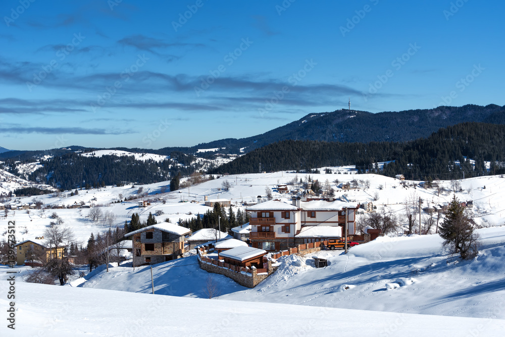 Winter forest scene. Small houses at the mountain in a sunny winter day. Snowy fairytale in Bulgaria.