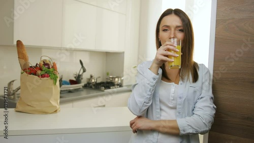 Atractive young woman drinking orange juice in the kitchen. photo