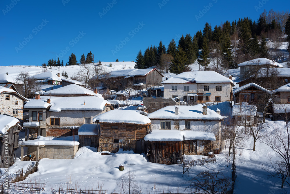 Winter forest scene. Small houses at the mountain in a sunny winter day. Snowy fairytale in Bulgaria.