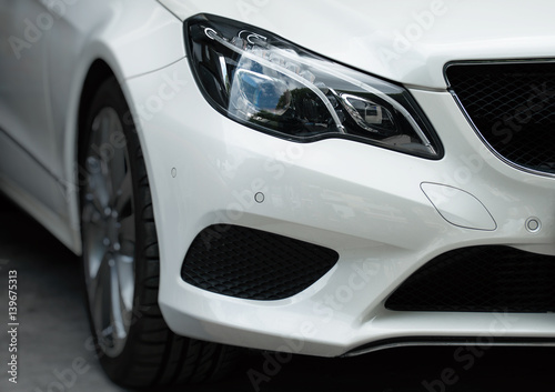 Close-up view of white sports car headlight.