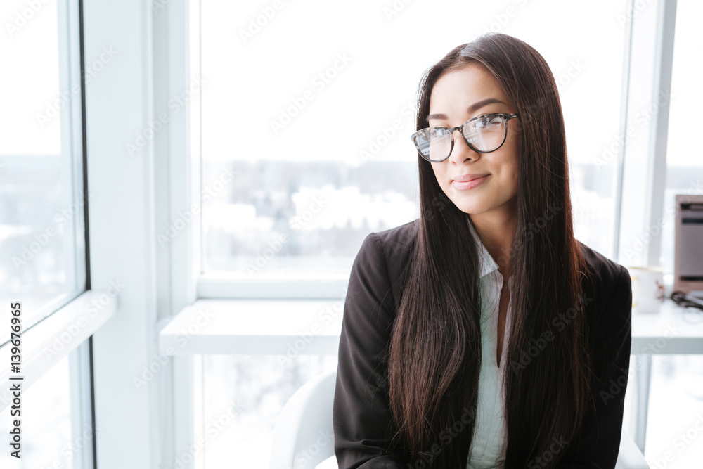 Smiling charming asian young businesswoman standing near the window