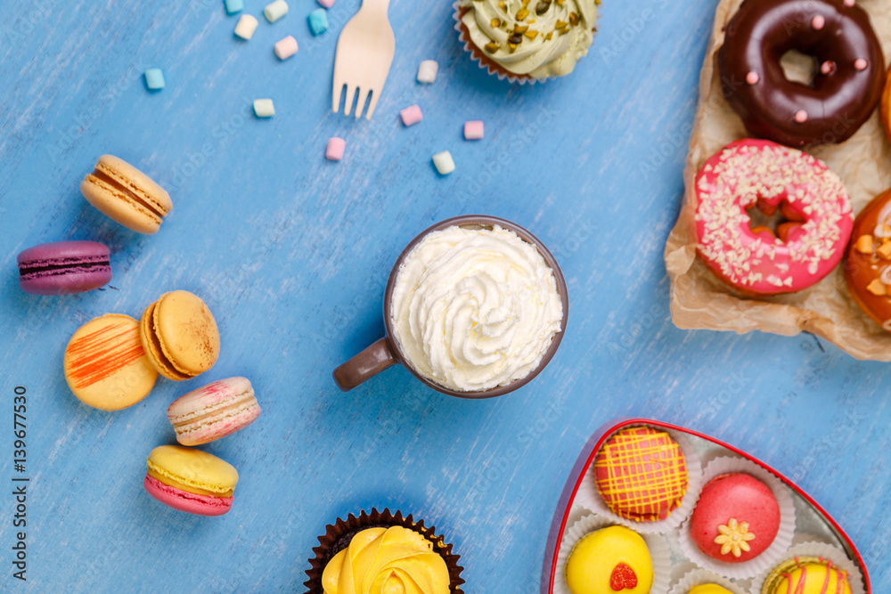 Cupcakes, macaroons and donuts. Mug with whipped cream. Almond macaron cookies with marshmallows. Sweet dessert. Cupcakes, macaroons and donuts. Mug with whipped cream. Almond macaron cookies with marshmallows. Sweet dessert.