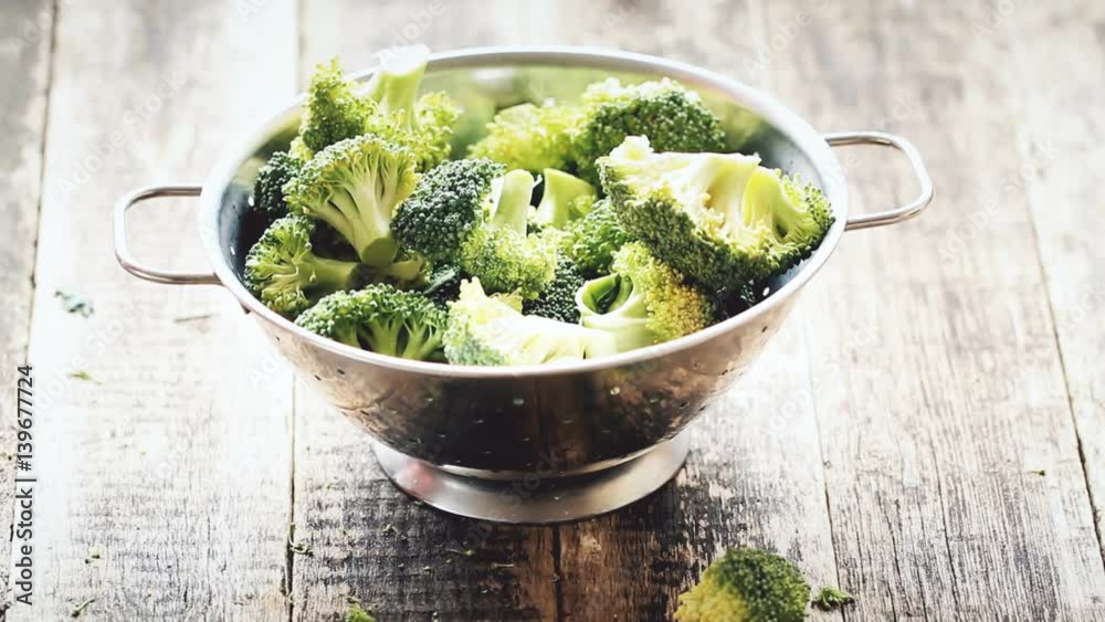 Fresh broccoli in stainless steel colander on old wooden background