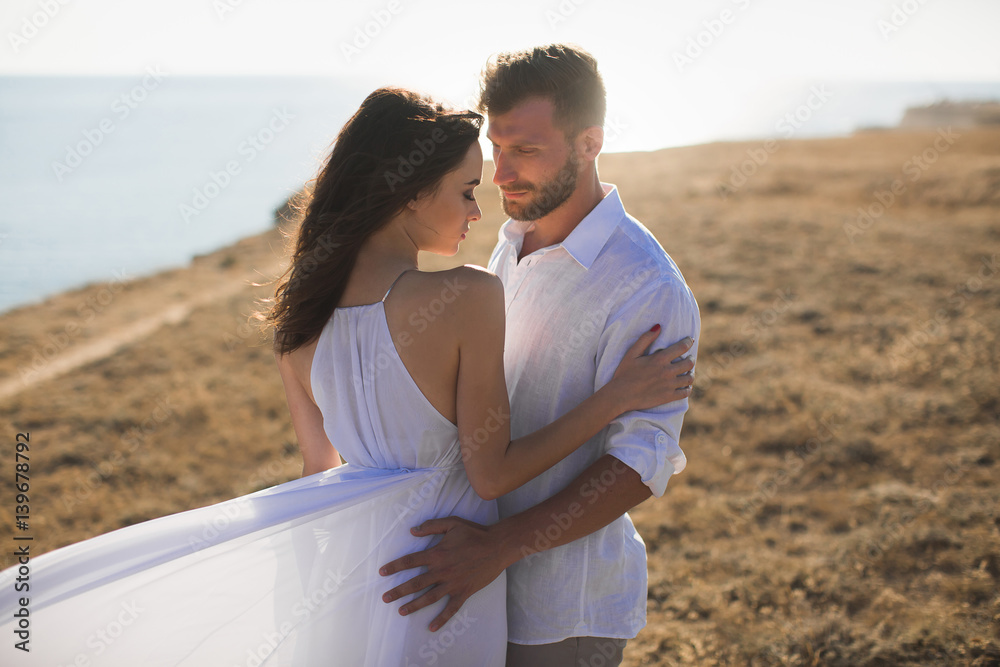 Beautiful young couple hugging in nature. People in white clothes.
