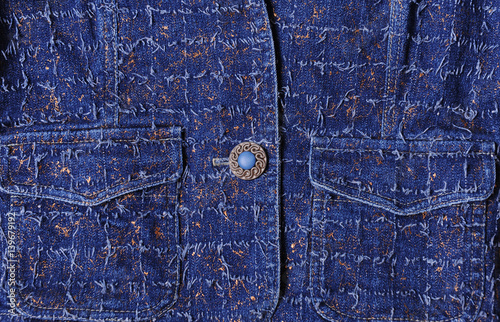 Texture of blue denim with gold threads. Beautiful blue button, pockets