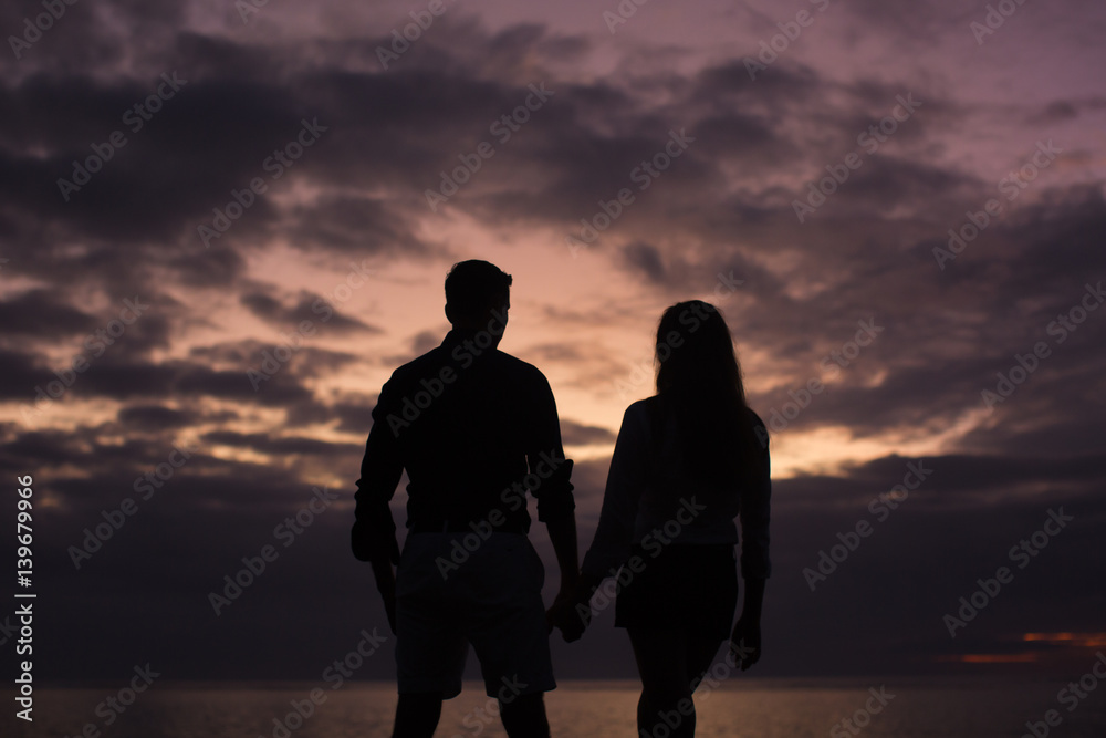 Young couple enjoying the sunset on the beach