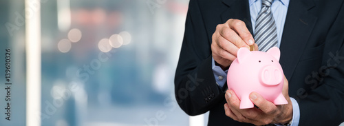 Fotografija Man putting money in a piggy bank