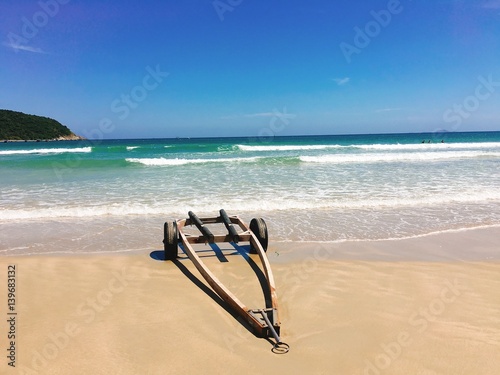 Fototapeta Naklejka Na Ścianę i Meble -  The wheelbarrow on the beach with sea wave foam