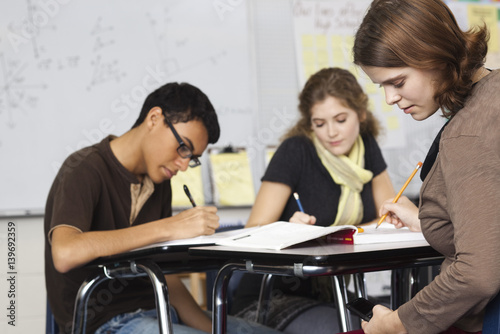 Students working in class, one text messaging under her desk