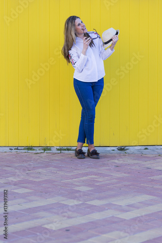 beautiful young woman with hat and sunglasses having fun. Yellow background. Lifestyle