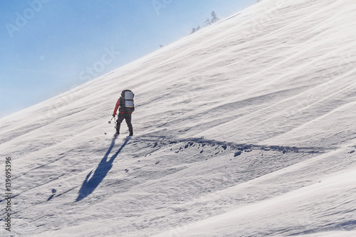 Alone skier hiking with a backpack in winter mountains slopes photo