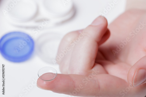 Girl holds a contact lens on the index finger