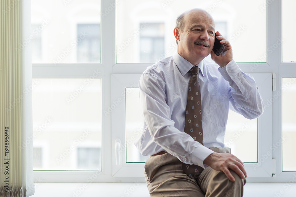 elderly businessman conducts informal talks on the phone elderly businessman conducts informal talks on the phone